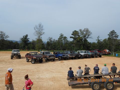 2013 Ford Bronco - A group of off-road vehicles are gathered in a dirt lot on a cloudy day.