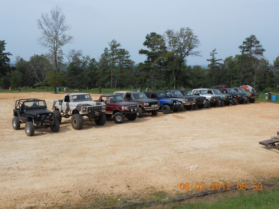 Line of lifted off-road trucks and SUVs parked on dirt lot