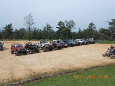 2013 Ford Bronco - A collection of off-road vehicles are parked in a dirt lot on a sunny day.