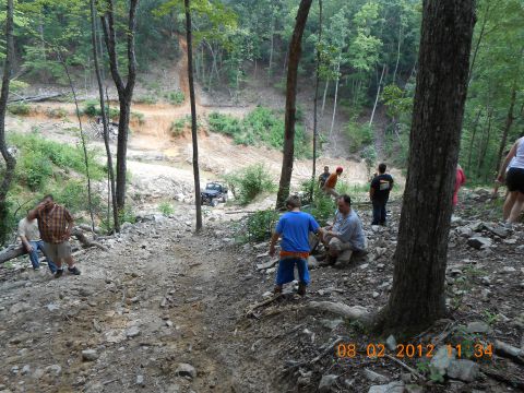 2013 Ford Bronco - A group of people watch a Jeep navigate a challenging off-road trail in a wooded area.