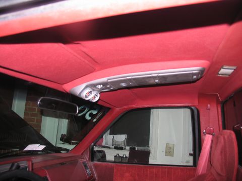 1990 Chevrolet Silverado 1500 - The interior of a red truck cab features a custom headliner with added gauges and a rearview mirror.