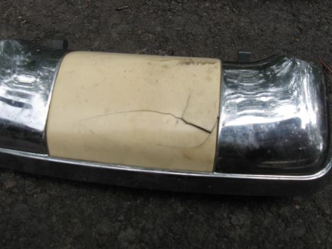 1990 Ford Bronco - Close-up of a damaged bumper part with chrome accents and a cracked plastic section.