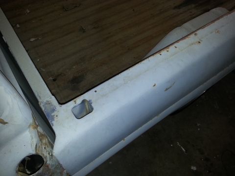 1967 Ford F-100 - The corner of a truck bed shows weathered wooden planks and a light blue painted metal side with signs of rust.