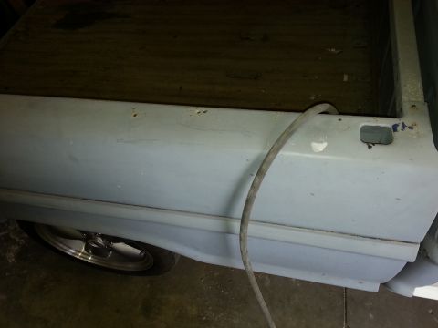 1967 Ford F-100 - Side view of a 1967 Ford F-100 truck bed panel, showing a hose and a chrome wheel.