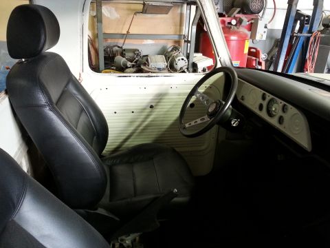 1967 Ford F-100 - The interior of a 1967 Ford F-100 shows black leather seats and a white dashboard with multiple gauges.