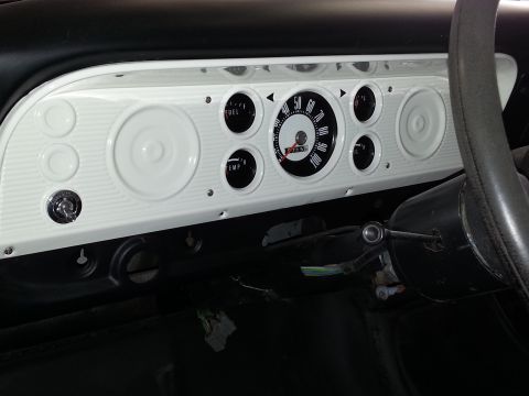 1967 Ford F-100 - The white instrument panel of a 1967 Ford F-100 features a central speedometer and auxiliary gauges for fuel and temperature.