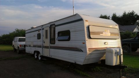 1995 Ford Bronco - A travel trailer is parked next to a white SUV in a grassy area.