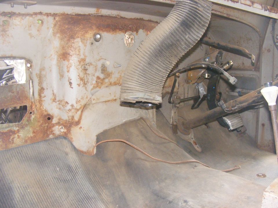 rusted interior of old vehicle, showing floor, pedals, and a flexible air duct
