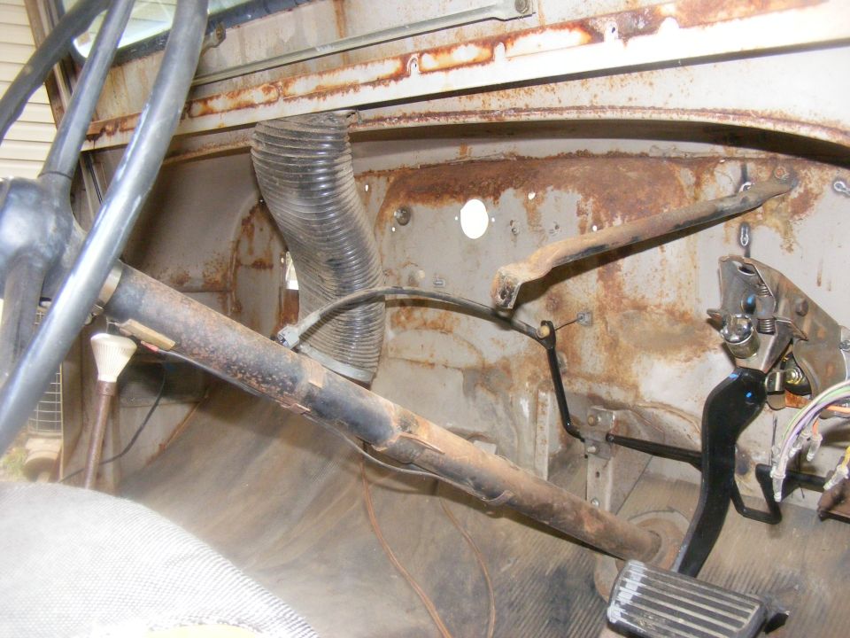 Rusty vehicle interior with steering column, floor pedals, and flexible ducting