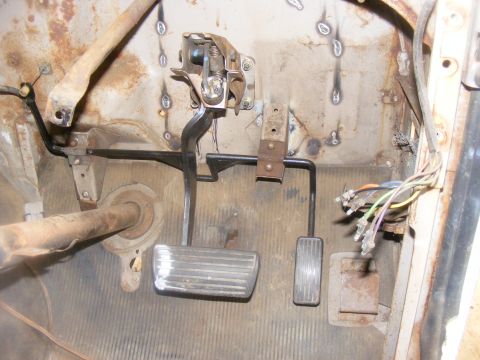 1978 Ford Bronco - Close-up of the interior footwell, showing the brake and clutch pedals and a bundle of wires. The Supermotors.net logo is visible in the lo…