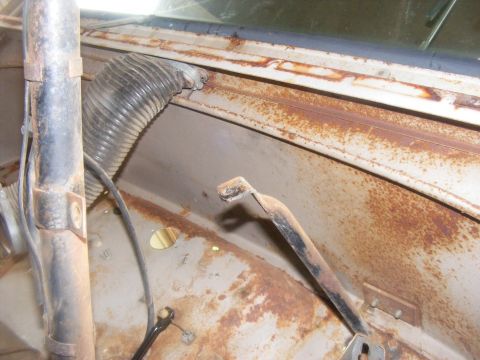 1978 Ford Bronco - Interior view of a vehicle showing extensive rust and a flexible hose.