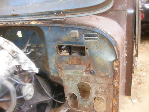 1978 Ford Bronco - Close-up of a heavily rusted vehicle firewall, showing exposed metal and some wiring. The year is not discernible from the image.
