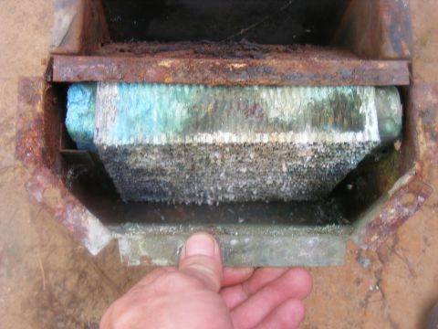 1978 Ford Bronco - A hand holds a heavily corroded radiator part, showing extensive mineral buildup and rust.