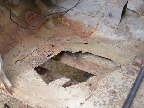 1978 Ford Bronco - The interior floor pan of a vehicle shows extensive rust and deterioration, with large sections missing.