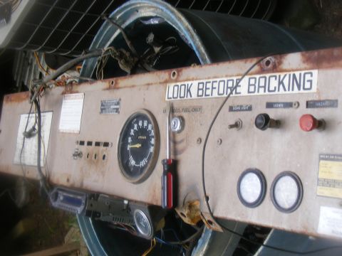 1978 Ford Bronco - A weathered dashboard panel displays various gauges and switches, including a 'LOOK BEFORE BACKING' warning.