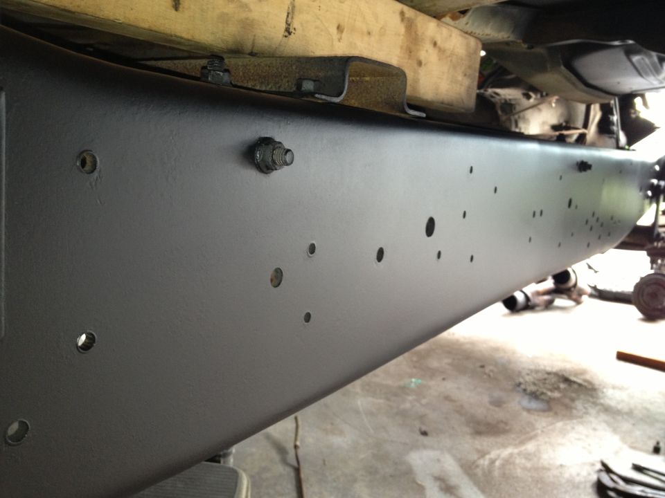 Black painted truck frame with visible bolt heads and mounting holes