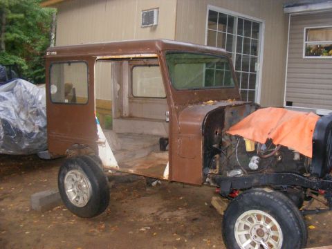 1978 Ford Bronco - This vehicle chassis, possibly a Jeep, is undergoing restoration. The engine is partially covered, and the body is a rusty brown.