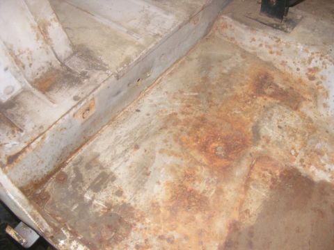 1978 Ford Bronco - The interior floor of a vehicle shows significant rust damage and wear.