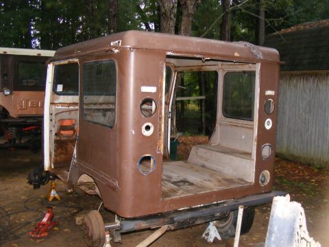 1978 Ford Bronco - A brown van body, possibly a postal vehicle, sits on jack stands with another vehicle in the background.