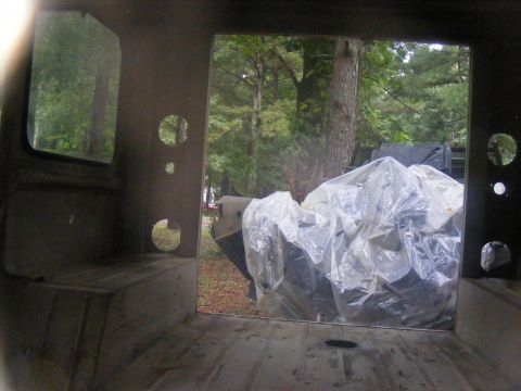 1978 Ford Bronco - View from inside a vehicle, showing trees and a large object covered in plastic sheeting.