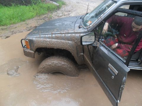 1987 Toyota 4Runner - A driver navigates a muddy trail in a 1987 Toyota 4Runner, getting stuck in a deep puddle.