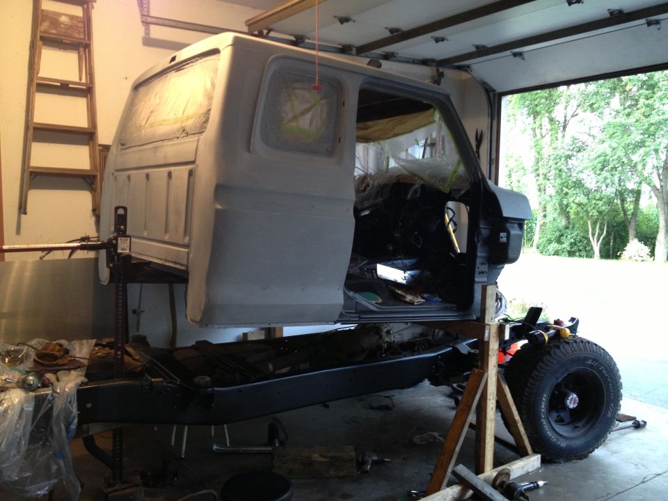 1979 Ford F-350 cab and chassis disassembled in a garage, supported by jacks