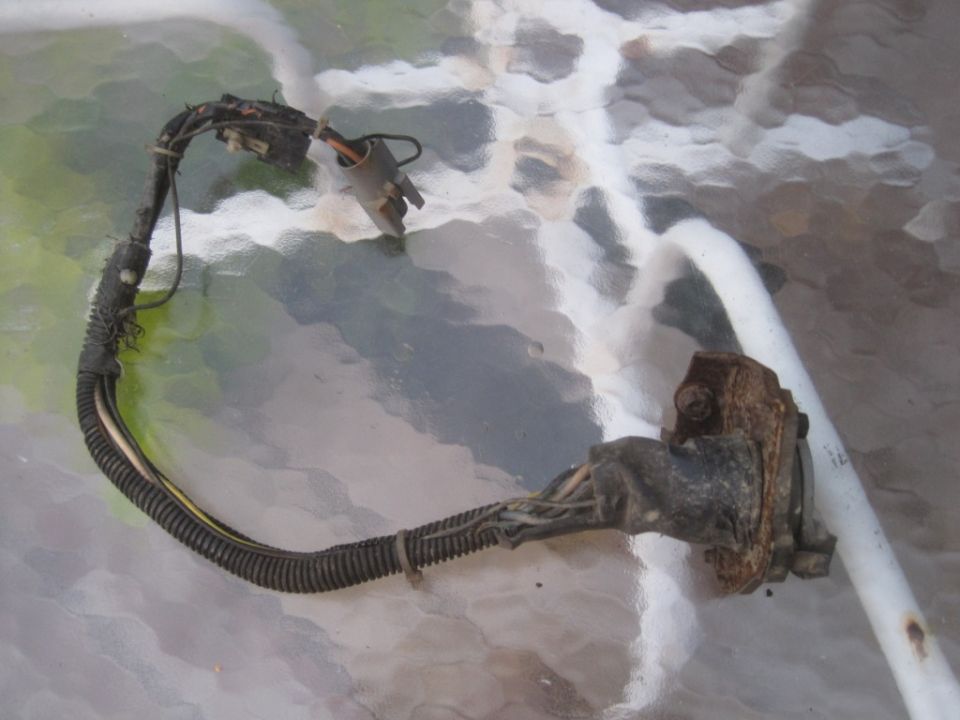 Wiring harness with connectors and frayed insulation, resting on a textured surface