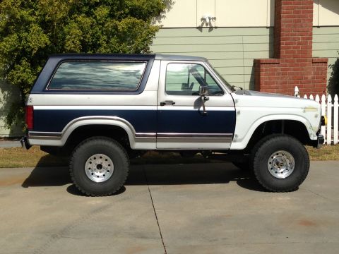 1986 Ford Bronco - This lifted Ford Bronco features a two-tone paint scheme with dark blue and silver accents.