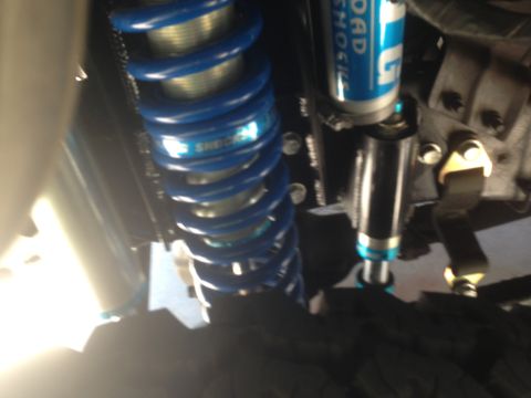 1986 Ford Bronco - Close-up view of a blue coilover shock absorber, with visible text indicating 'SHOCK'.
