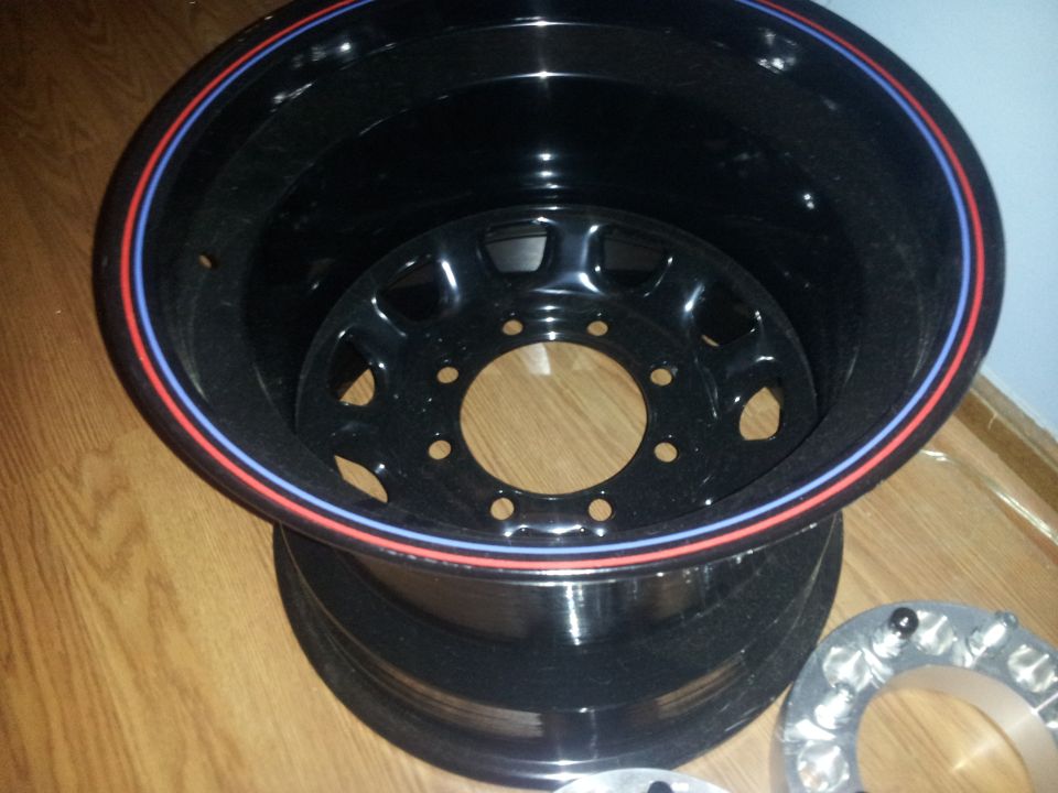 Black aftermarket wheel with red and blue pinstripe on the lip, showing inner wheel spokes