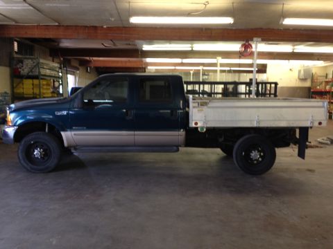 1999 Ford F-250 - This 1999 Ford F-250 crew cab pickup features a utilitarian flatbed, seen here in a workshop setting.