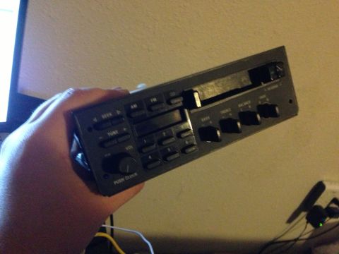 1992 Ford F-150 - A person is holding a car stereo unit that has various buttons and knobs for audio control.