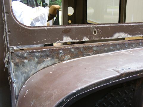 1978 Ford Bronco - Close-up of a vehicle's rusted body panel, showing signs of repair and primer.