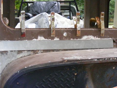 1978 Ford Bronco - A close-up of a vehicle's bodywork shows repairs in progress with metal clamps holding a new panel in place.