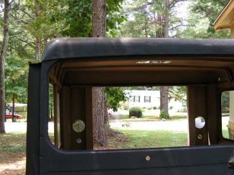 1978 Ford Bronco - The interior of a vintage truck cab shows a view of a suburban yard and house through the open windows.