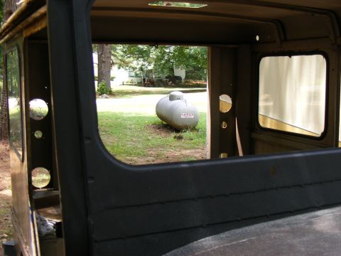 1978 Ford Bronco - View from inside a vehicle shows a propane tank in the yard, with the vehicle's interior visible in the foreground.