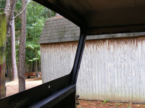 1978 Ford Bronco - View from inside a 1978 Ford Bronco, showing the interior frame against a backdrop of trees and a wooden shed.