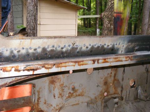 1978 Ford Bronco - Close-up of a heavily rusted metal panel, showing evidence of repair work with spot welds.
