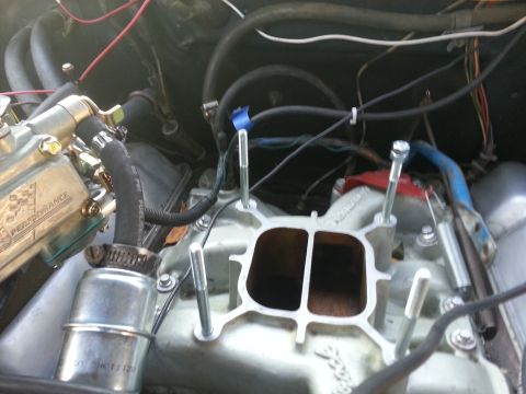 1978 Ford Bronco - Close-up view of an engine's intake manifold and carburetor assembly, with bolts ready for installation.