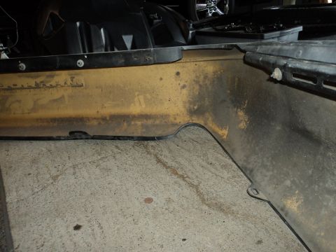 2004 Mercury Grand Marquis - Close-up of a yellow car bumper section with visible dirt and grime, showing part of the black trim.