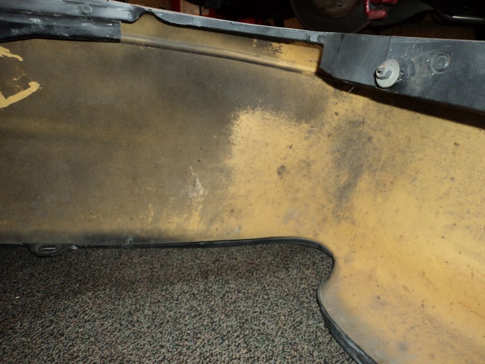 Yellowish car part with black trim and a screw fastener