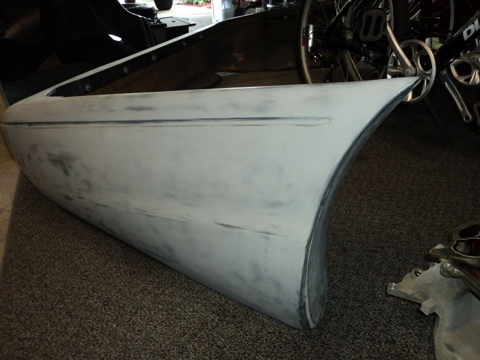 Gray car door with primer, showing a curved edge and a horizontal body line