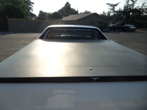 1973 Ford Ranchero - The rear of a vehicle with a tonneau cover is shown, with other cars parked in the lot.