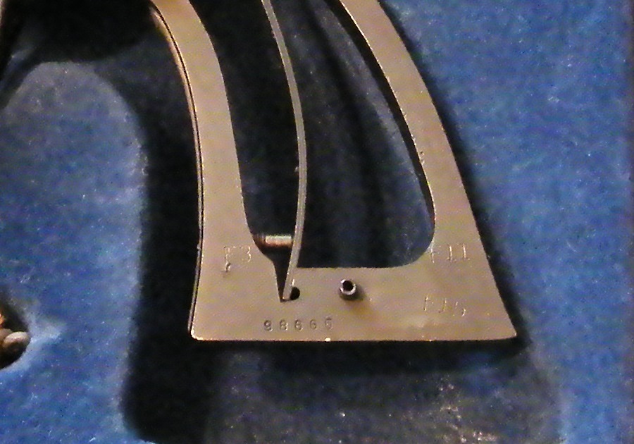 Close-up of a metal part with stamped numbers '98665' and other markings