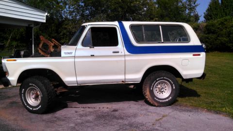 1979 Ford Bronco - A white and blue Ford Bronco is parked outside with its hood open, revealing engine components.