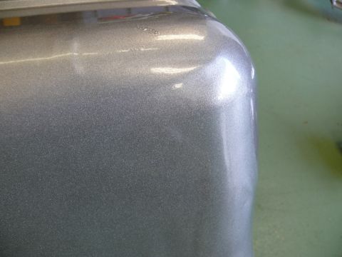 1976 Chevrolet Corvette - A close-up view of a metallic silver car fender shows some minor damage and reflections.