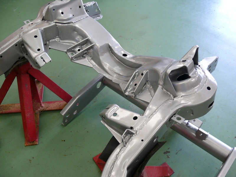 Silver painted car frame chassis sections supported by red jack stands