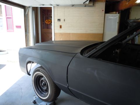 2001 Ford Crown Victoria - A gray sedan, possibly undergoing restoration, is parked inside a garage with the front fender and wheel in view.