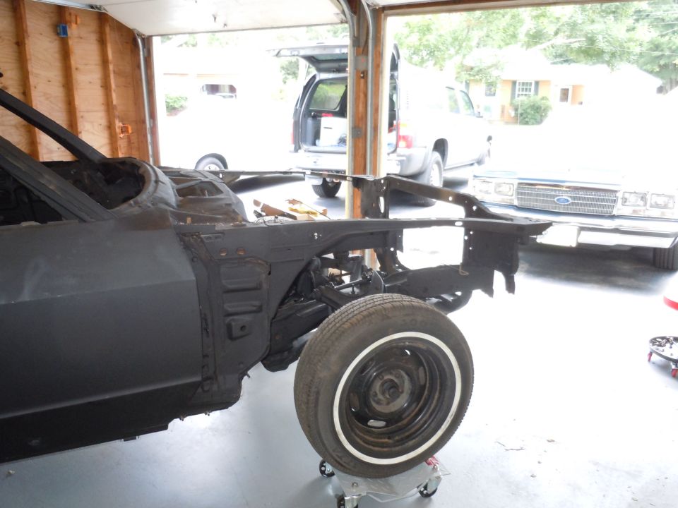 car body on dolly in garage, another car and SUV in background