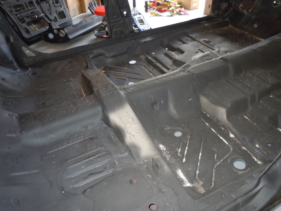Stripped car interior floor pan, showing structural supports and mounting holes